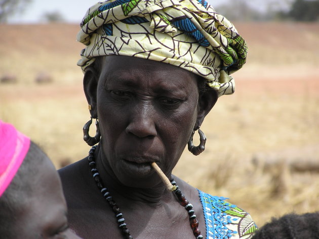 Vrouw uit Gambia die met behulp van een stokje haar tanden reinigt