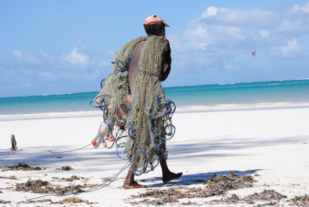 Een eenzame, hardwerkende visser op het strand van Diani Beach.