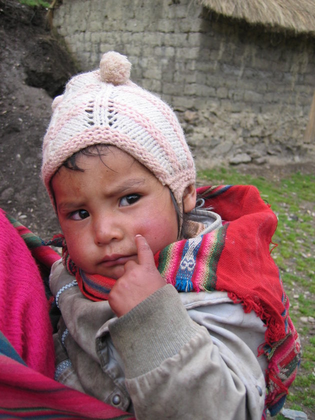 een baby op de rug van een inwoonster van Patakacancha