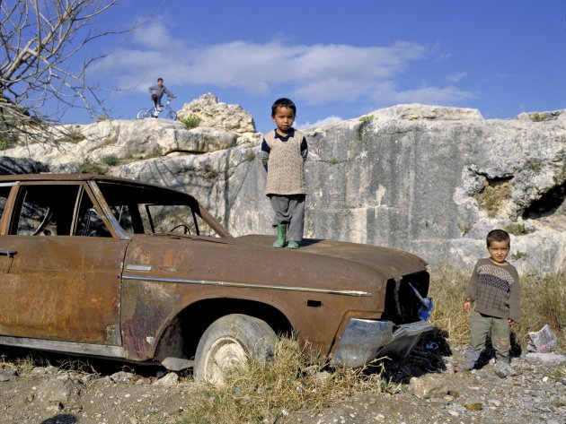 spelend kind staat op oude verroeste auto