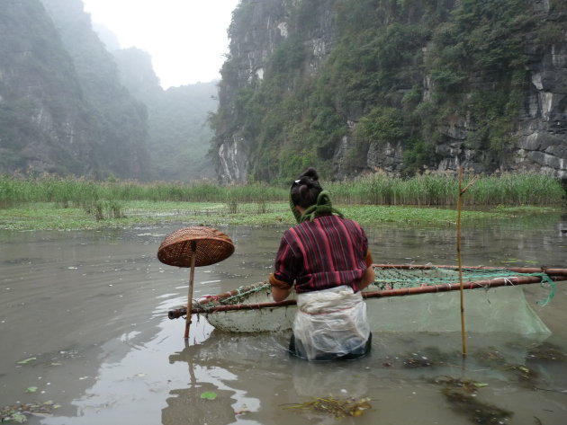 Vietnamese vrouw hangt visnetten op bij Can Tho