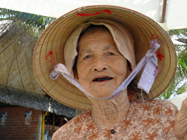 Oude vrouw op het strand van Hoi An