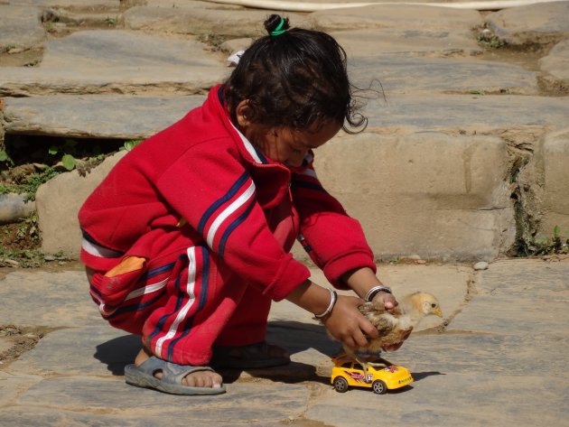 Meisje speelt met kuiken en auto, Bandipur