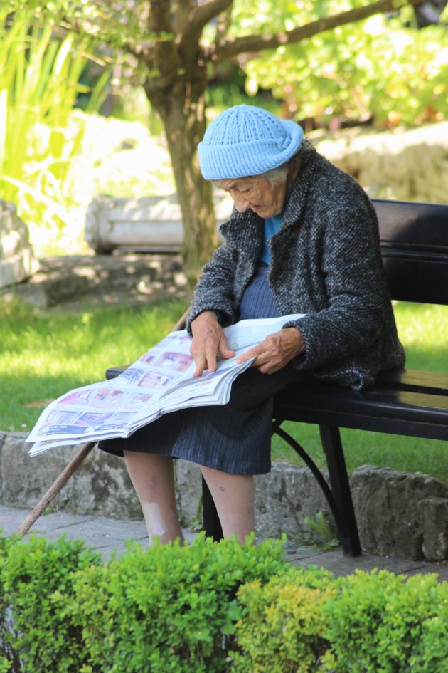 Oud vrouwtje geniet van haar krant