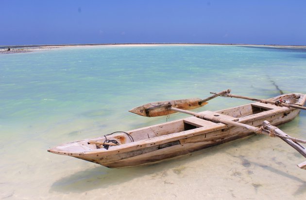 Vissersboot bij eb op het strand van Zanzibar