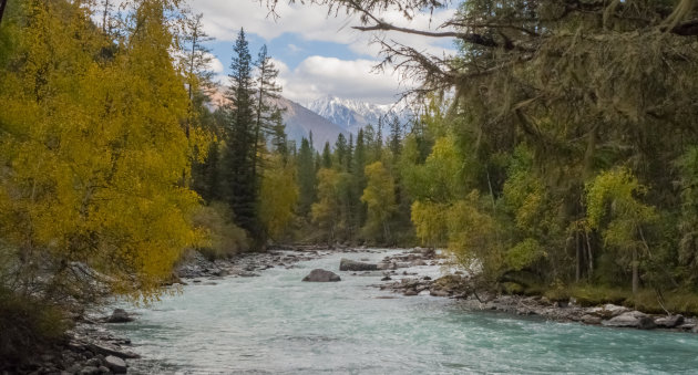 De ijskoude rivier snijdt door de warme herfstkleuren