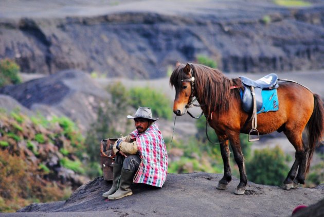 Een Javaanse man en zijn paard pakken even een rustmoment bij de Bromo vulkaan